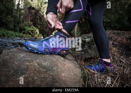 Weibliche strafft Schnürsenkel vor Lauf. Stockfoto
