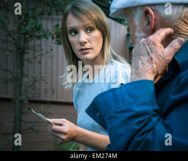 Eine junge Frau und ein älterer Mann sitzt auf einer Bank sitzend im Gespräch. Stockfoto