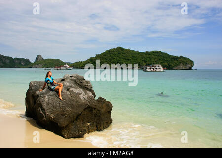 Junge Frau sitzt auf einem Felsen am Wua Talab Insel, Ang Thong National Marine Park, Thailand Stockfoto