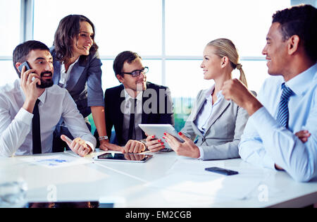 Glückliche Mitarbeiter besprechen Ideen im Büro Stockfoto