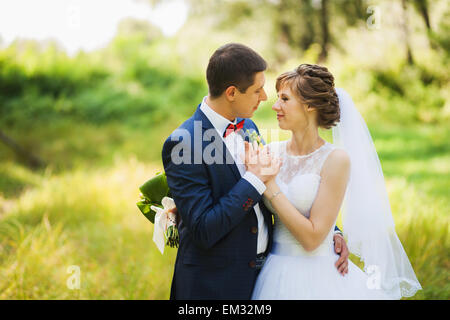 glückliche Braut, Bräutigam stehen im grünen Park, küssen, Lächeln, lachen, umarmen. Liebhaber in Hochzeitstag. Stockfoto