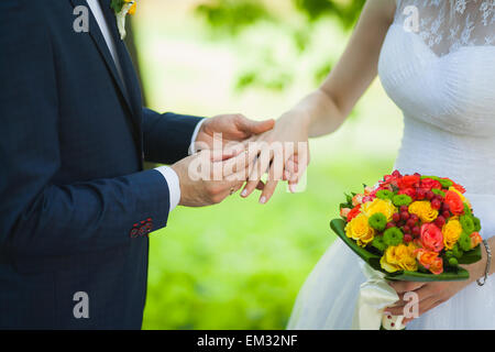 Nahaufnahme der Hände der unkenntlich Brautpaar mit Trauringe. Braut hält Hochzeit Blumenstrauß Stockfoto