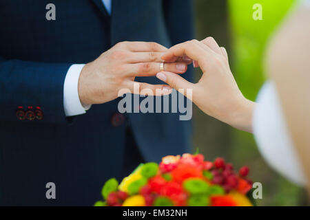 Nahaufnahme der Hände der unkenntlich Brautpaar mit Trauringe. Braut hält Hochzeit Blumenstrauß Stockfoto