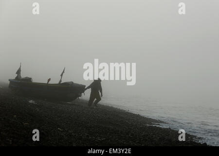 Ein Fischer bereitet sich auf sein Boot für einen Morgenfischen zu starten, wie ein Meer Nebel in Brighton in East Sussex rollt Stockfoto