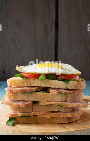 Sandwich mit geräuchertem Schweinefleisch, Tomaten und Spiegelei vertikale Stockfoto