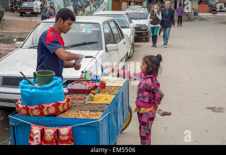 Nepalesische Mädchen kaufen Pop Corn von einem Straßenhändler in Kathmandu, Nepal Stockfoto