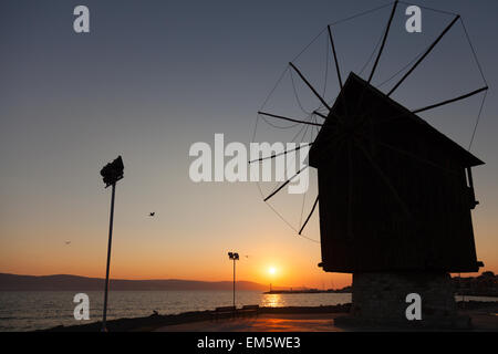 Schwarze Silhouette in der Morgensonne. Alte hölzerne Windmühle an der Küste, die beliebtesten Wahrzeichen der Altstadt von Nessebar, Bulgarien Stockfoto