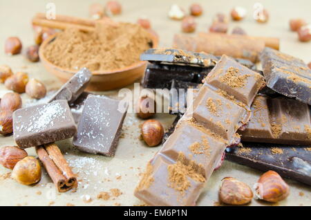 Jede Menge Schokolade Stöcke, Zimt und Haselnüsse auf einem Tisch Stockfoto