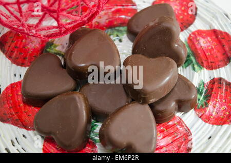 Herrlich auf der Suche nach Schokolade auf einem Erdbeer gemusterten Decoupage-Brett in Herzform Stockfoto