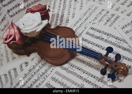 Alte Geige mit Musiknoten und rose Nahaufnahme Stockfoto