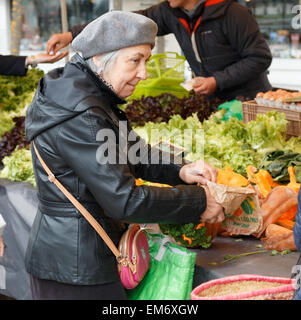 Ältere Dame Gemüse in einem französischen Markt zu kaufen.  Die senior Französin trägt eine Baskenmütze. Stockfoto