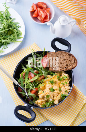 Rührei mit frischen Tomaten und Rucola Salat in Pfanne, Ansicht von oben Stockfoto