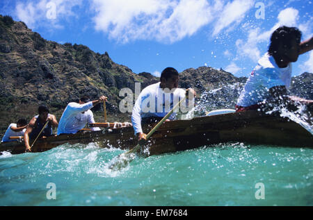 Hawaii, Oahu, Waimanalo Bay, Männer paddeln Auslegerkanus im türkisblauen Wasser. Kein Model-Release Stockfoto