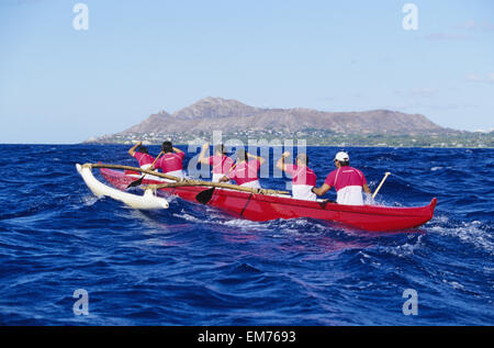 Hawaii, Oahu, Männer paddeln Auslegerkanus, Rückseite des Diamond Head In Ferne, Ansicht von hinten. Kein Model-Release Stockfoto