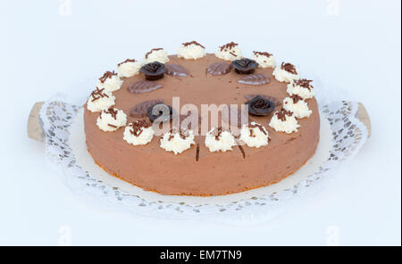 Schokoladen-Sahne-Torte auf weißem Hintergrund mit Kuchen-Spitze. Stockfoto