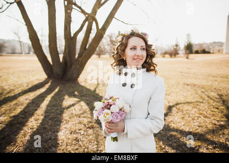 Schöne junge Frau mit zarten Blüten im Haar und Blumenstrauß in Händen Stockfoto