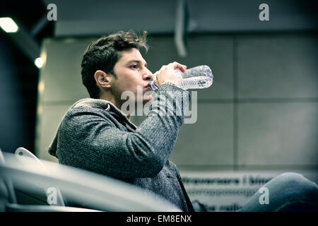 Junger Mann im Zug Bahnhof Trinkwasser aus Kunststoff-Flasche Stockfoto