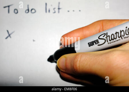 Eine weiße Hand einen Sharpie Stift eine "To do-Liste" auf ein Blatt Papier schreiben. Stockfoto