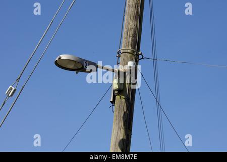 Traditionelle hölzerne Telegrafenmast mit einer Straßenlaterne vor dem tiefblauen Himmel Stockfoto