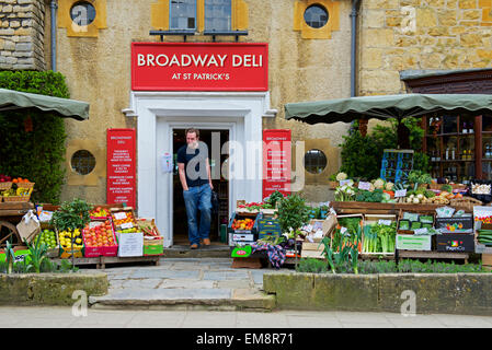 Mann zu Fuß aus dem Broadway Deli in Cotswolds Dorf Broadway, Worcestershire, England UK Stockfoto