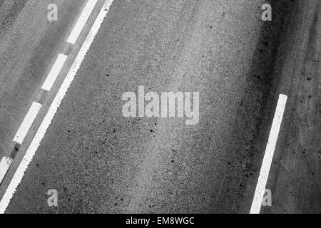 Asphaltstraße mit Trennlinien und Reifenspuren. Hintergrundtextur Foto Stockfoto