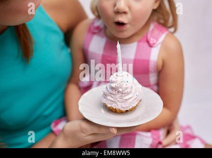 glückliche Mutter und Mädchen Kuchen Kerze ausblasen Stockfoto