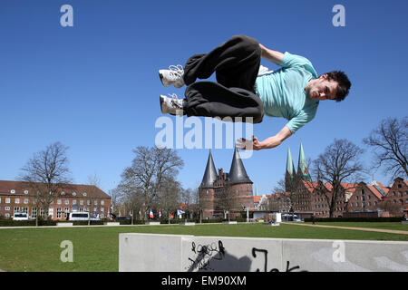 Lübeck, Deutschland. 15. April 2015. Nils Marckwardt trainiert der Sport "Parcours" und führt einen "freien laufenden Sprung" mit einem Flip bei frühlingshaften Temperaturen und strahlendem Sonnenschein in Lübeck, 15. April 2015. Das Holstentor liegt im Hintergrund. Foto: BODO MARKS/Dpa/Alamy Live-Nachrichten Stockfoto