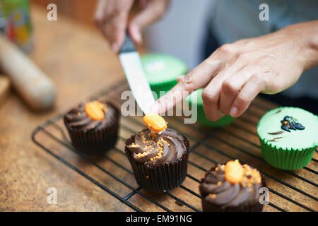 Womans Hände Vereisung Tasse Kuchen auf Rack-Kühlung Stockfoto