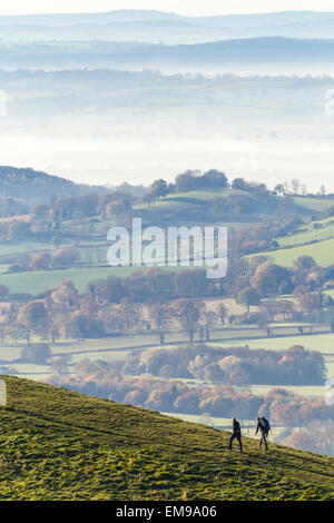 Zwei Menschen, die zu Fuß über Sugarloaf Berg auf Malvern HIlls mit Hereford-Tal im Nebel im Hintergrund Stockfoto