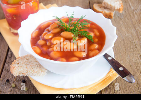 Bohnen in Tomaten-Sause mit Dill auf hölzernen Hintergrund schließen sich horizontal Stockfoto