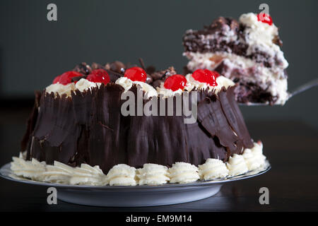 Schokoladenkuchen mit Sahne und Kirschen, serviert wird. Stockfoto