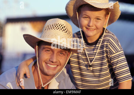 Glücklich Porträt von Vater und Sohn tragen Cowboy Strohhüte im freien Stockfoto