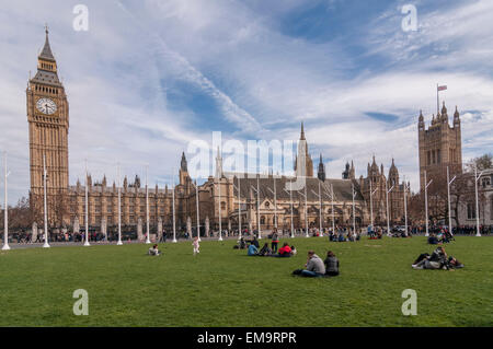 London, UK. 17. April 2015. UK-Wetter: Touristen nutzen das schöne Wetter zum Entspannen auf der Rasenfläche des Parliament Square, Westminster, während von Big Ben und den Houses of Parliament übersehen. Bildnachweis: Stephen Chung / Alamy Live News Stockfoto