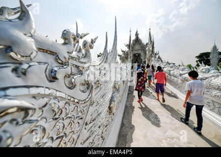 Chiang Rai, Thailand. 17. April 2015. Touristen überqueren Sie die Brücke des "Zyklus der Wiedergeburt" auf dem Weg zum Ubosot Halle des Wat Rong Khun in Chiang Rai, Thailand, 17. April 2015. Wat Rong Khun, allgemein bekannt als Tempel des weißen ist ein buddhistischer Tempel gestaltet und im Besitz von thailändischen Künstlers Chalermchai Kositpipat. Mit weißen architektonischen Strukturen, die mit silbrigen reflektierenden Folien sowie dekorativen zeitgenössischen Gemälden geschmückt, dient Wat Rong Khun als ein beliebtes Touristenziel in Chiang Rai. © Li Mangmang/Xinhua/Alamy Live-Nachrichten Stockfoto