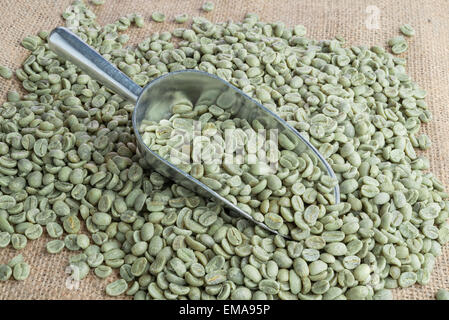 Grüne Kaffeebohnen in Metall Schaufel auf Sackleinen Oberfläche Stockfoto