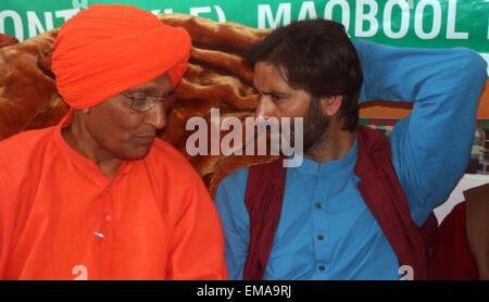 Srinagar, indische verabreicht Kaschmir. 18. April 2015. Vorsitzender der Jammu Kaschmir Liberation Front (GEISELN) Yasin Malik, sitzt für einen 30-Stunde-langen Hungerstreik mit sozialer Aktivist Swami Agnivesh, in Safranrobe, sitzen in Unterstützung in Srinagar, indische Kaschmir gesteuert. Malik zusammen mit seinen Anhängern begannen einen 30-stündigen Hungerstreik aus Protest Indiens Plan, Townships für Hindus zu bauen, die einen Aufstand in mehrheitlich muslimischen Gebiete geflohen späteren Separatisten-Führer Yasin Malik und Swami Agnivesh, von der indischen Polizei Kredit festgenommen wurden: Sofi Suhail/Alamy Live News Stockfoto