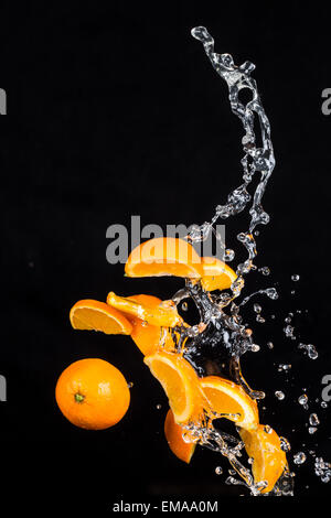 Frische Orangen mit Wasser spritzt isolierten auf schwarzen Hintergrund Stockfoto