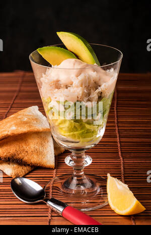 Krabben Sie Fleisch cocktail Salat mit Melba Toast --Salat Avocado Krabben und Marie-Rose Sauce mit einer Scheibe Zitrone Stockfoto