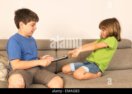 Kinder, die sich für das Spielen mit einem digitalen Tablet auf einem Sofa. Stockfoto