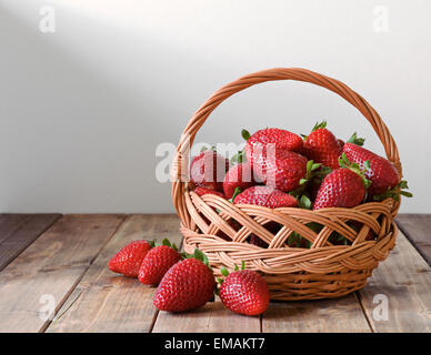 reife Erdbeeren in einem Weidenkorb auf einem Holztisch Stockfoto