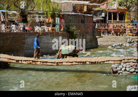 Ein Berber Mann an der Spitze seinen Esel über den Fluss im Dorf Setti Fatma im Ourika-Tal, Atlas-Gebirge in Marokko Stockfoto