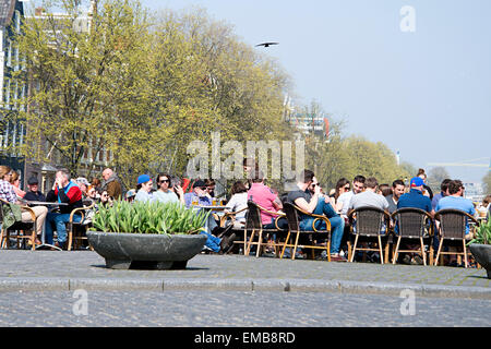 Touristen sitzen auf Torensluis Brücke über Singel Kanal trinken, Geselligkeit, die Sonne zu genießen. Stockfoto