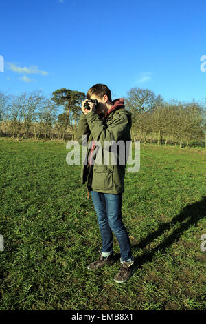 15-jähriger Junge, Foto mit 35mm Film Kamera im Feld im Winter bei Brabourne Lees, Ashford, Kent, England Stockfoto