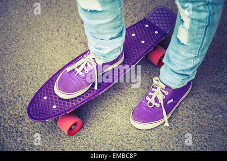 Jungen Skater in Detektive und Jeans auf seinem Skate stehen. Close-up-Fragment der Skateboard und Füße Stockfoto