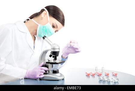 Ärztin oder wissenschaftlicher Mitarbeiter in der Maske mit Pipette und Mikroskop, Platz für Text. Stockfoto