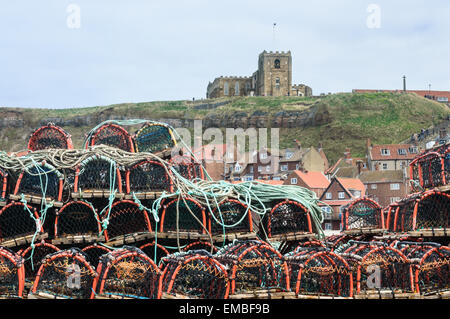 Stapel von Hummer Töpfe in den Hafen, mit der St. Maria Kirche im Hintergrund, in whitby, North Yorkshire, England. Am 18. April Stockfoto