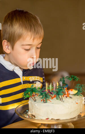 Sieben Jahre alter Junge Ausblasen der Kerzen auf seine Geburtstagstorte in Issaquah, Washington, USA Stockfoto