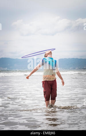 Junger Mann mit Hoola Hoop Ring zu spielen, am Strand, Riviera Nayarit, Pazifikküste, Mexiko Stockfoto