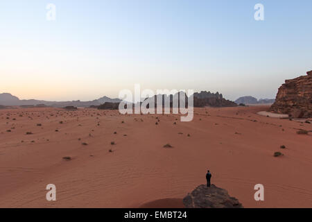 Wadi Rum, Jordanien - März 24,2015: Sonnenuntergang in der Wüste Wadi Rum, Jordanien, mit einem Mann beobachtete die Szene aus einem Felsen im Vordergrund Stockfoto