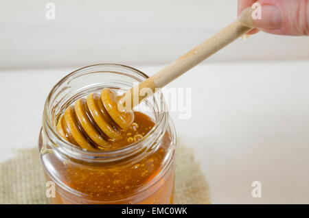 Honig in einem Glas aus einem speziellen Holzlöffel Tropfen Stockfoto